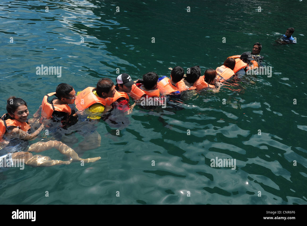 chain of swimmers swimming into  Morakot cave , the island of koh mook (also known as ko muk) , andaman sea ,thailand Stock Photo