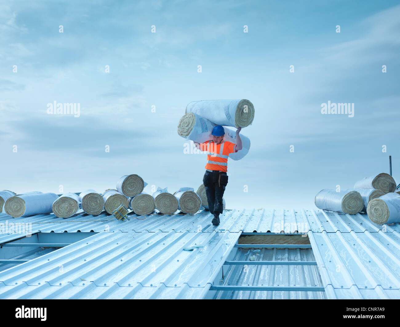 Worker carrying insulation on roof Stock Photo