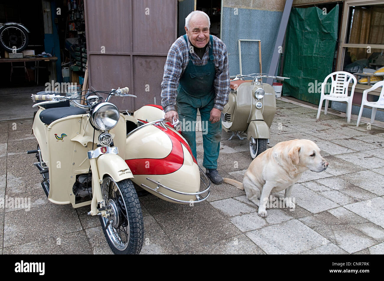portrait of retired mechanic with vintage Moto Guzzi, Lambretta and dog in Italy Stock Photo
