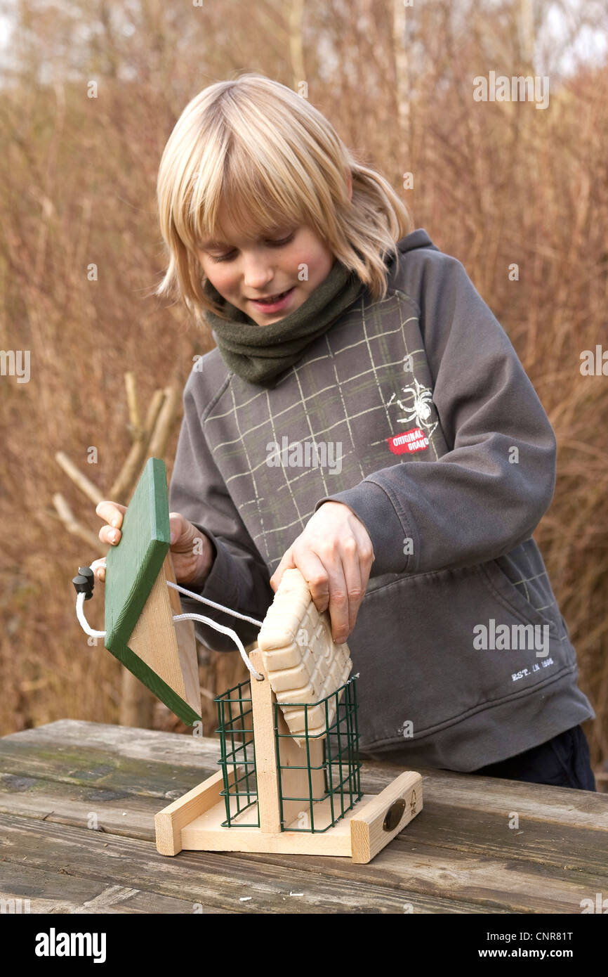 child filling suet into bird feeder Stock Photo