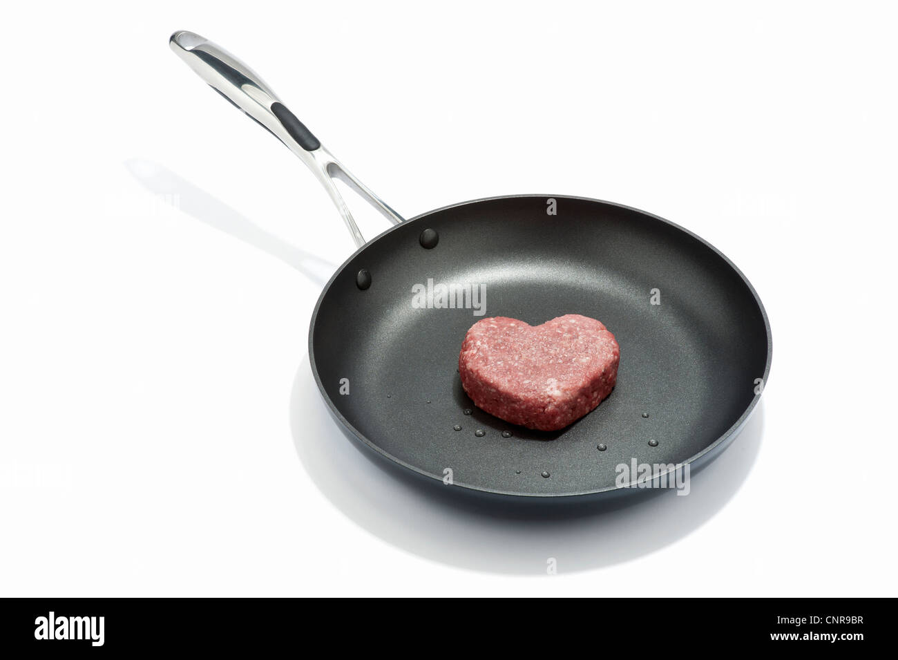 A heart shaped beef burger in a frying pan Stock Photo Alamy