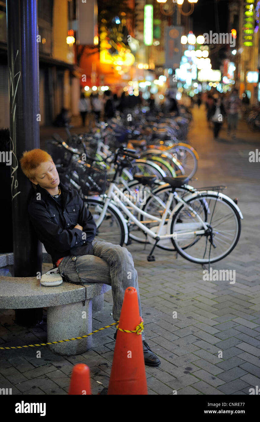 Young Japanese Man Sleeping Sitting On Stone Bench Osaka Japan