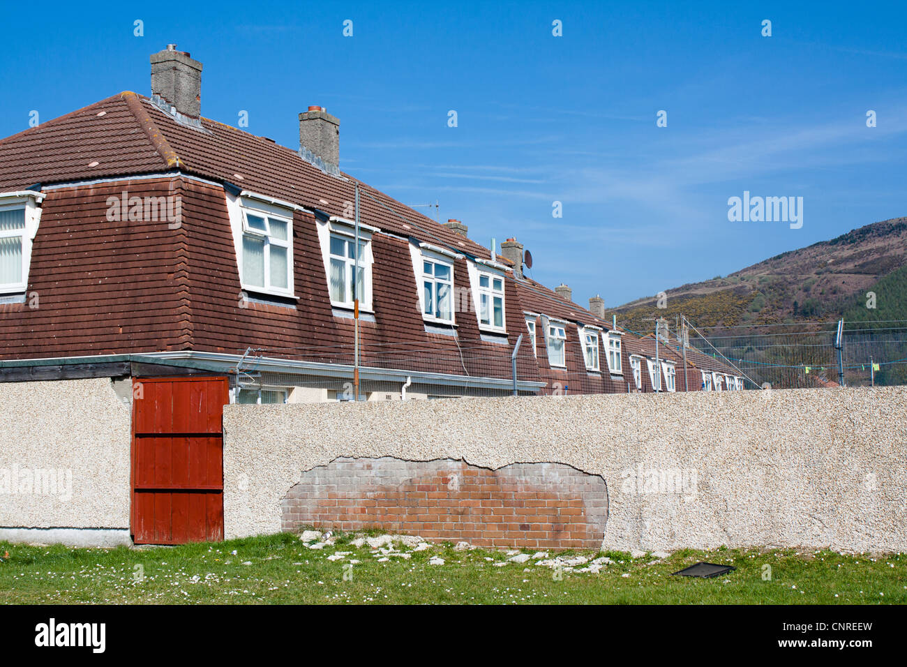 1950's Cornish houses with crumbling wall and mountain in the background. Stock Photo