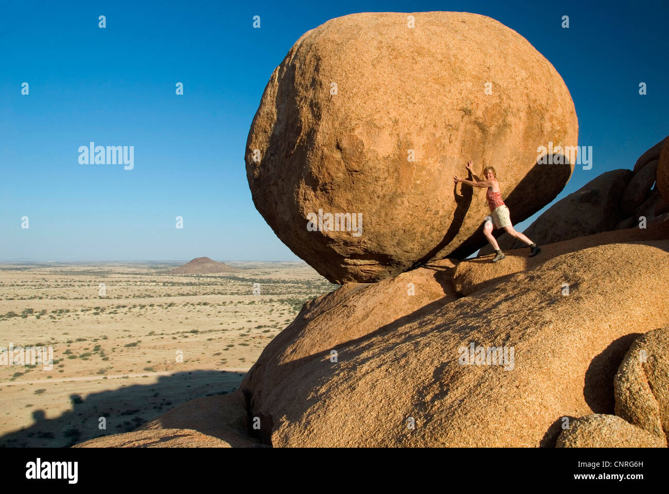 rock boulder Bushman's Paradise, Spitzkoppe. A woman tries to push the rock down, Namibia, Damaraland Stock Photo