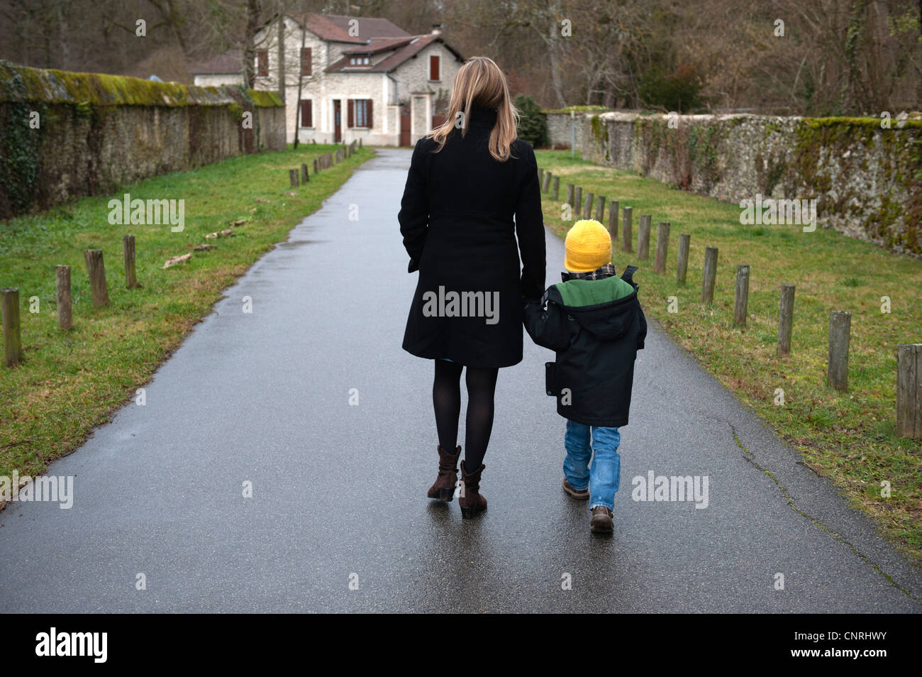 Mother And Son Walking On Path In Village Holding Hands Rear