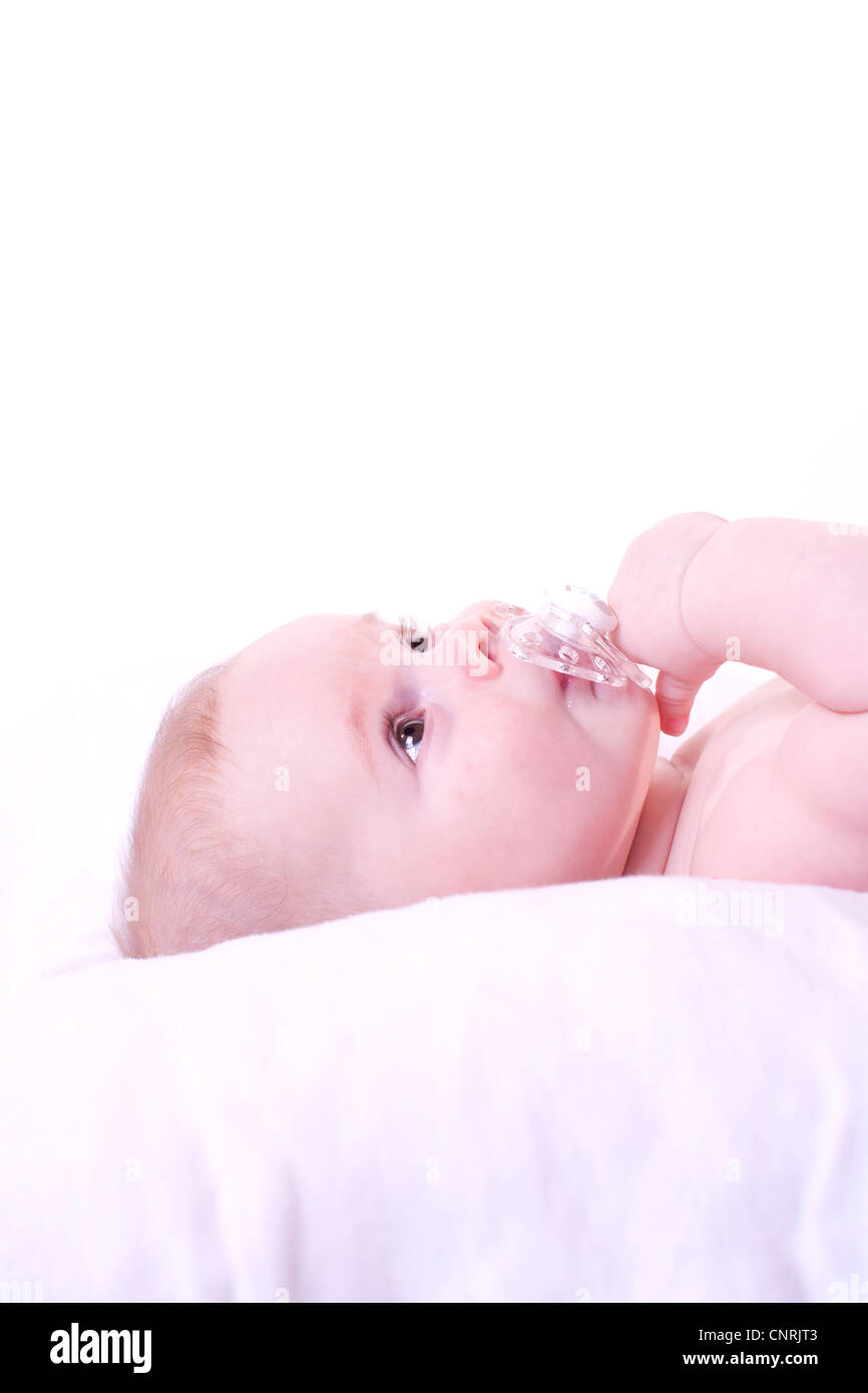 Baby lying down with pacifier in mouth Stock Photo