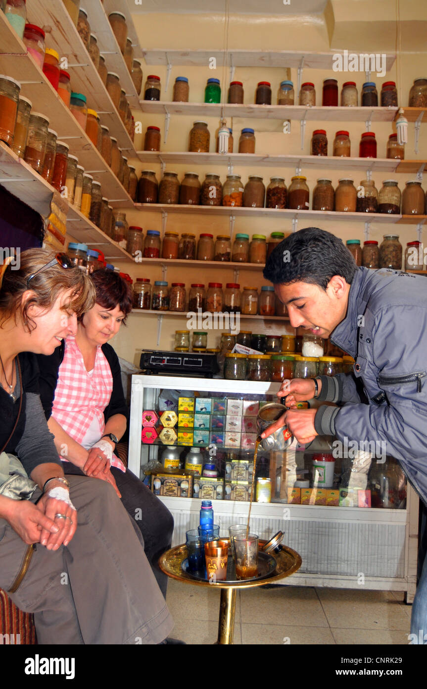 A spice salesman pours mint tea to tourists while trying to sell his spices Marrakesh Morocco Stock Photo