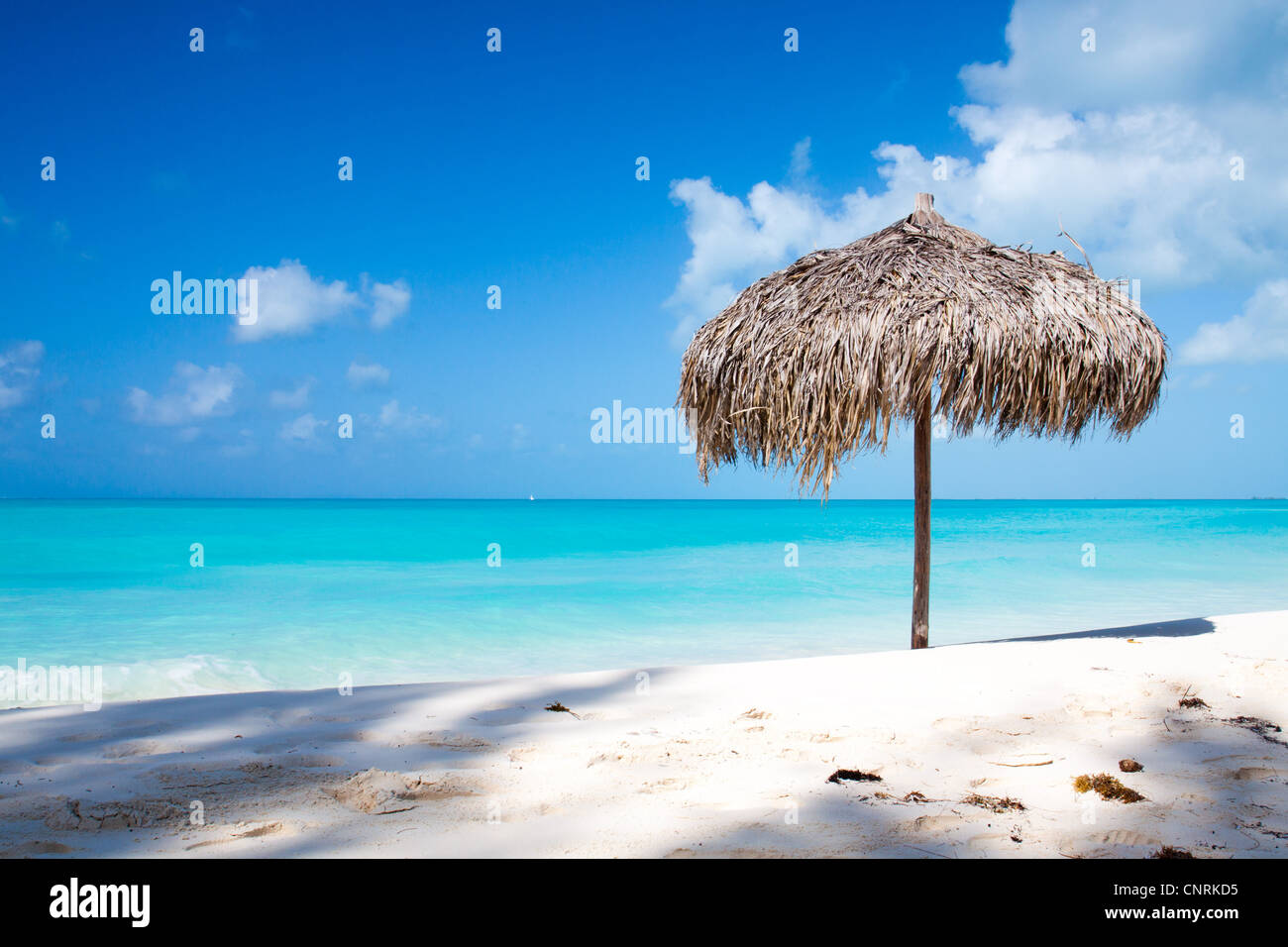 Beach Umbrella made of palm leafs on a perfect white beach in front of Sea. The right place for relax and vacations Stock Photo