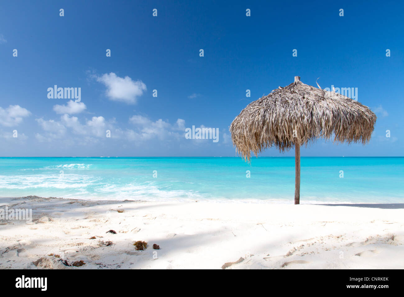 Beach Umbrella made of palm leafs on a perfect white beach in front of Sea. The right place for relax and vacations Stock Photo