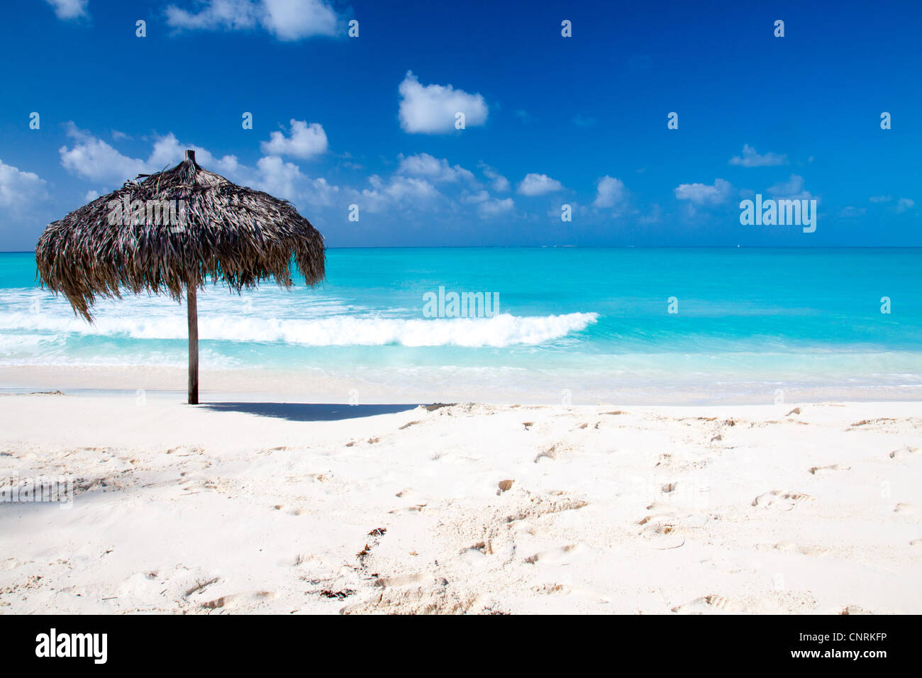 Beach Umbrella made of palm leafs on a perfect white beach in front of Sea. The right place for relax and vacations Stock Photo