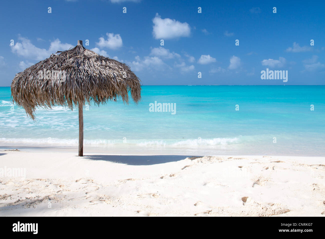 Beach Umbrella made of palm leafs on a perfect white beach in front of Sea. The right place for relax and vacations Stock Photo