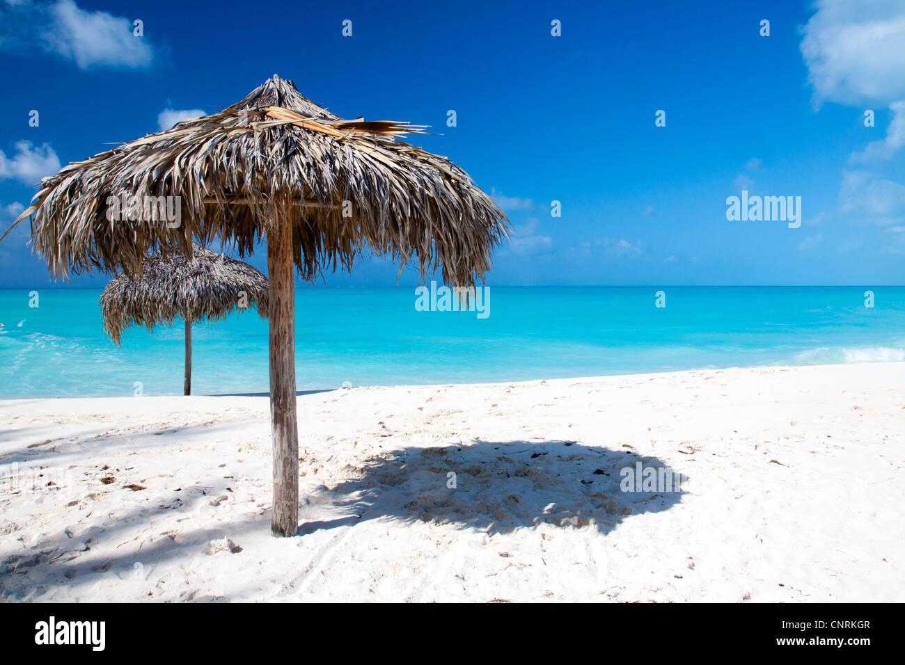 Beach Umbrella made of palm leafs on a perfect white beach in front of Sea. The right place for relax and vacations Stock Photo