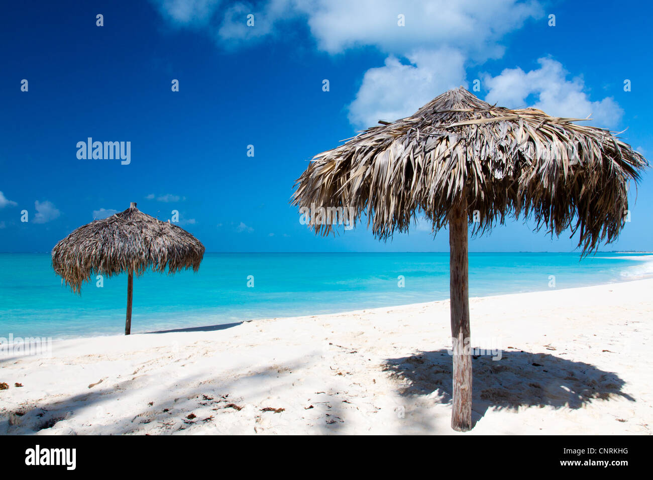 Beach Umbrella made of palm leafs on a perfect white beach in front of Sea. The right place for relax and vacations Stock Photo