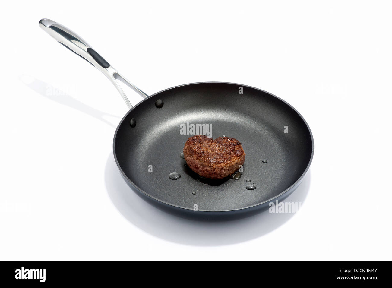 A heart shaped beef burger in a frying pan Stock Photo Alamy
