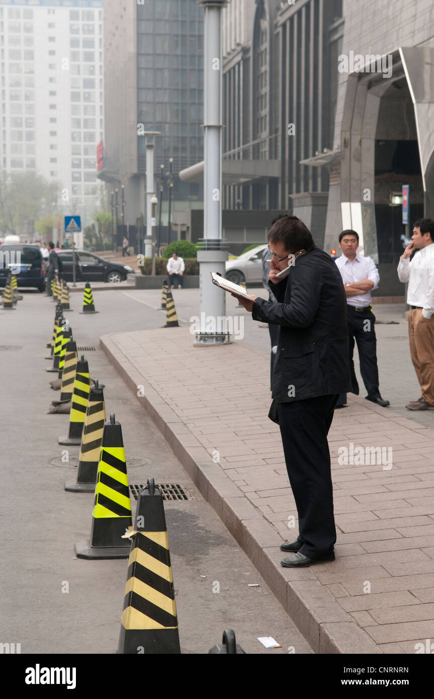 Businessman talking into a cellular telephone on the sidewalk of a chinese city Stock Photo