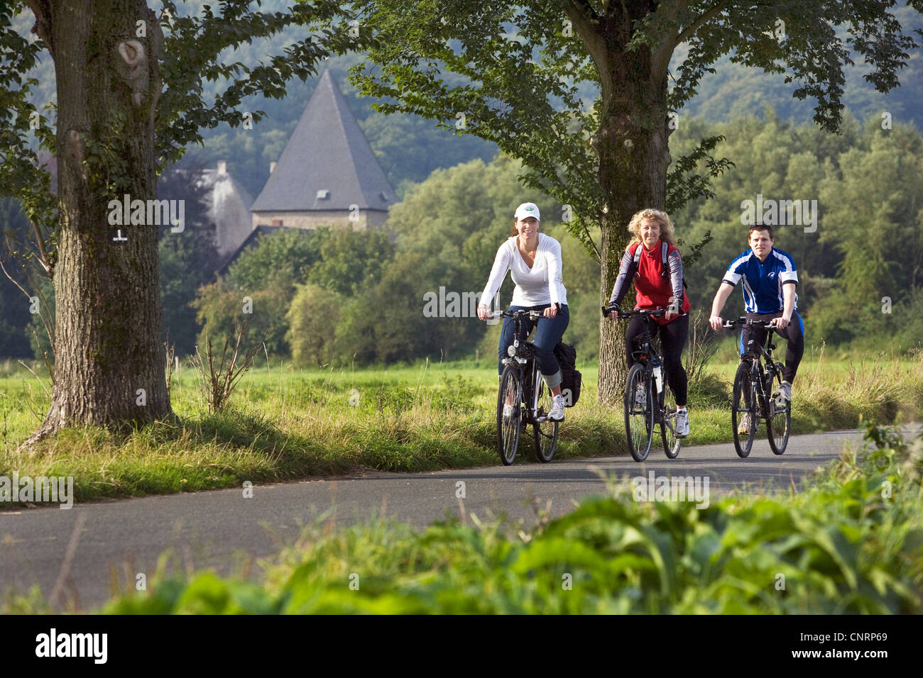 three persons cycling on the Ruhr Valley Cycleway, Kemnade castle in the background, Germany, North Rhine-Westphalia, Ruhr Area, Witten Stock Photo