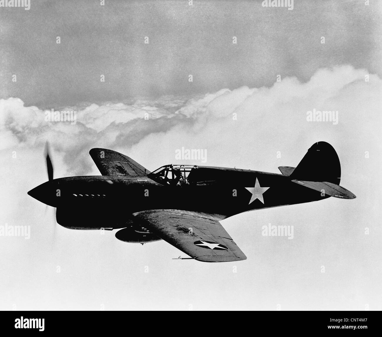 Vintage World War II photo of a P-40 fighter plane flying above the clouds. Stock Photo