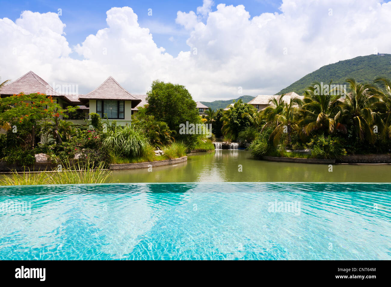 Tropical landscape of swimming pool, pond, holiday villas and trees. Stock Photo