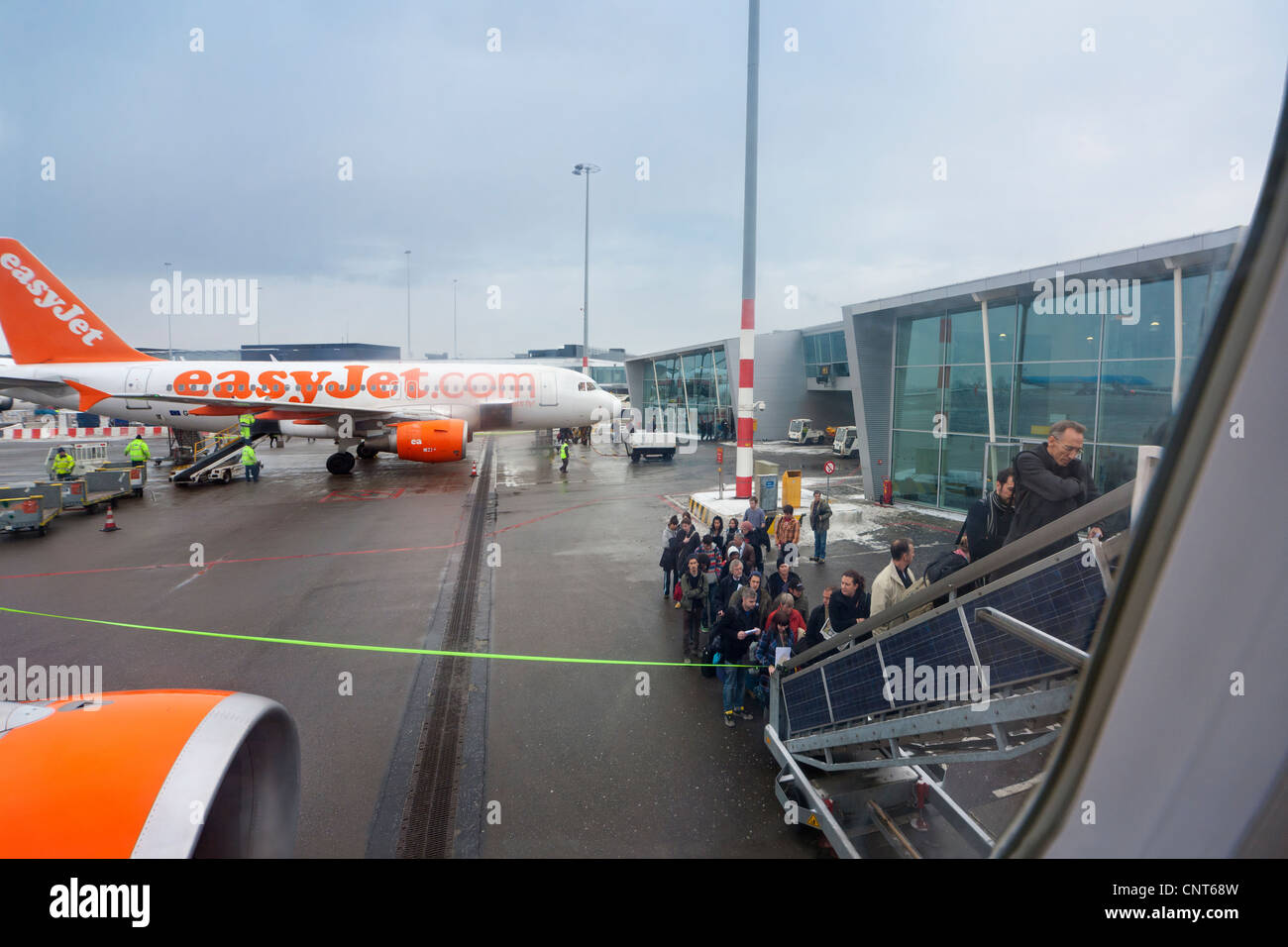 Amsterdam Schiphol Airport People boarding EasyJet plane airplane aeroplane mobile staircase stairs in winter. H Pier Stock Photo