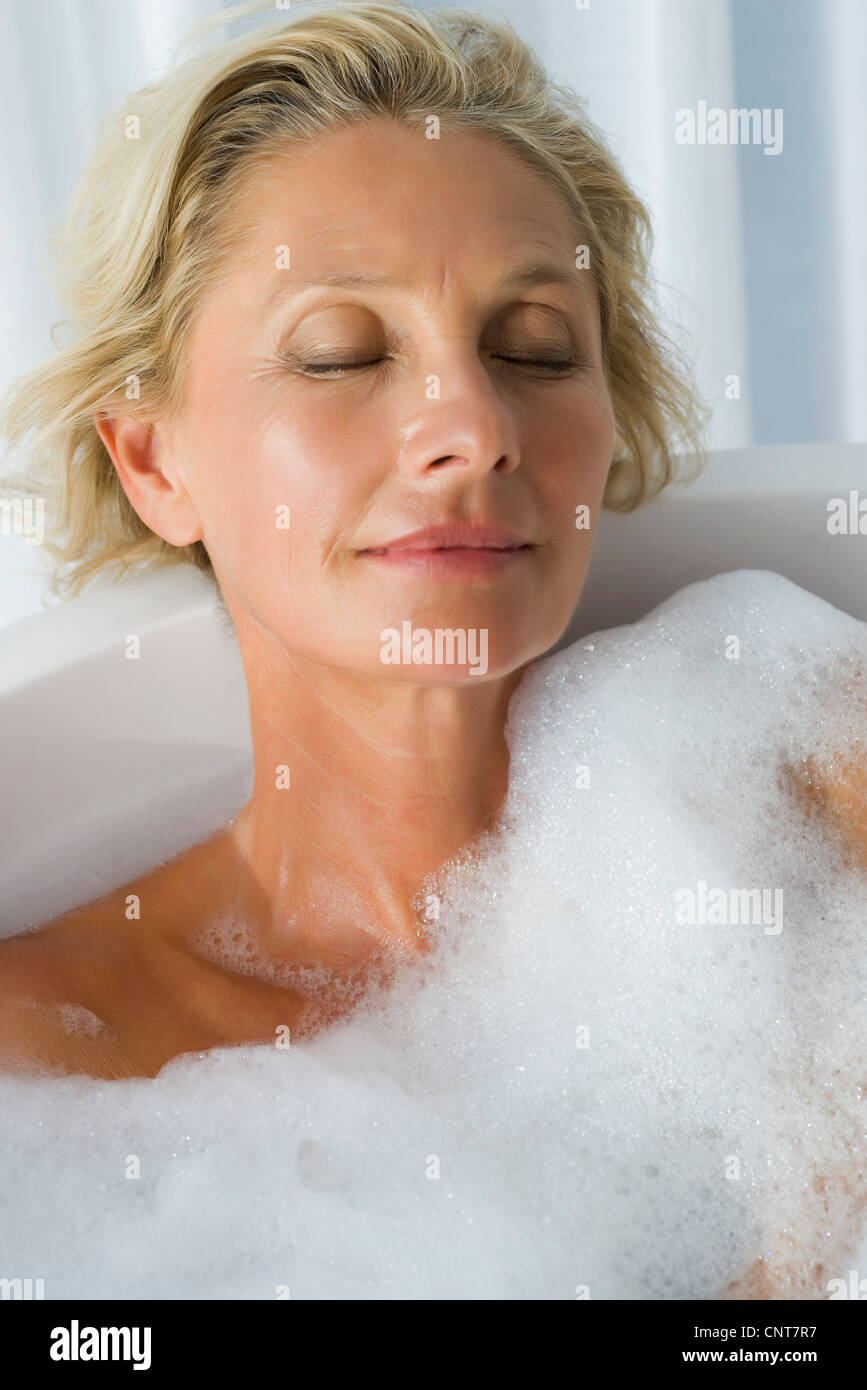 Mature woman relaxing in bubble bath with eyes closed, portrait Stock Photo