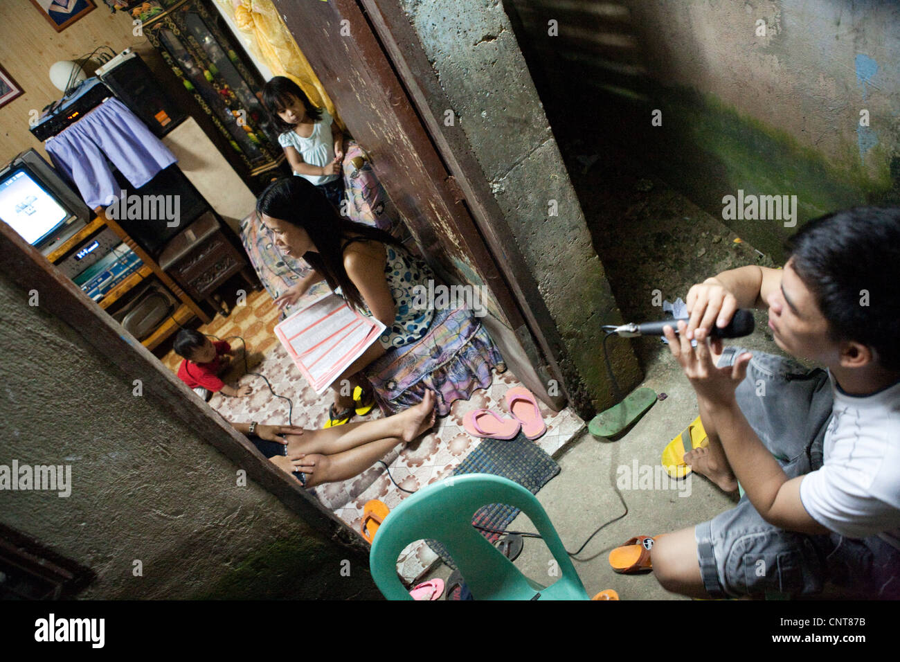 Filipino family together at home, singing karaoke. Lapu-Lapu City, Metro Cebu, Mactan Island, Visayas, Philippines. Stock Photo