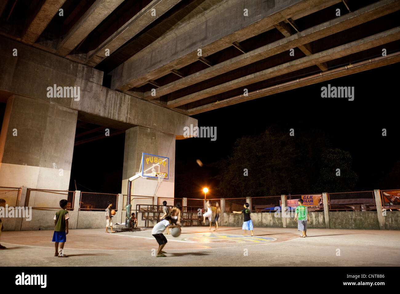 Filipino boys playing basketball underneath Marcelo Fernan Bridge. Lapu-Lapu City, Metro Cebu, Mactan Island Visayas Philippines Stock Photo