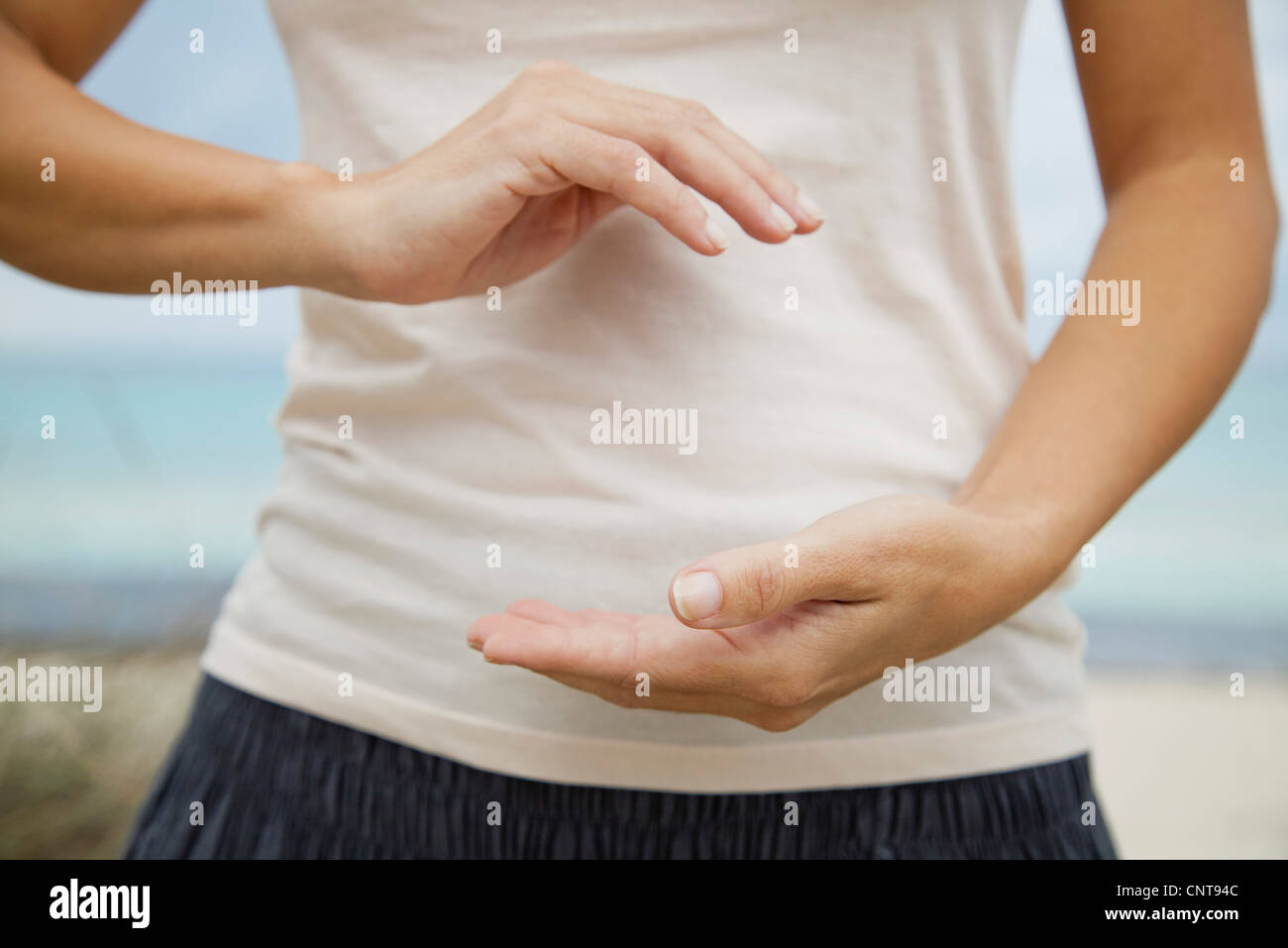 Woman doing 'hold the ball' tai chi chuan move, mid section Stock Photo