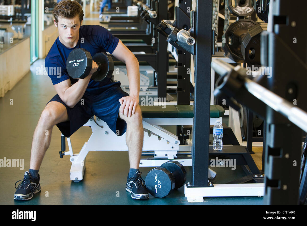 Young man lifting dumbbell in weight room Stock Photo
