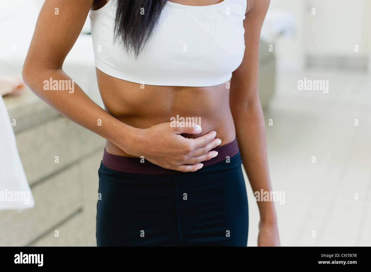 Woman experiencing abdominal pain, mid section Stock Photo