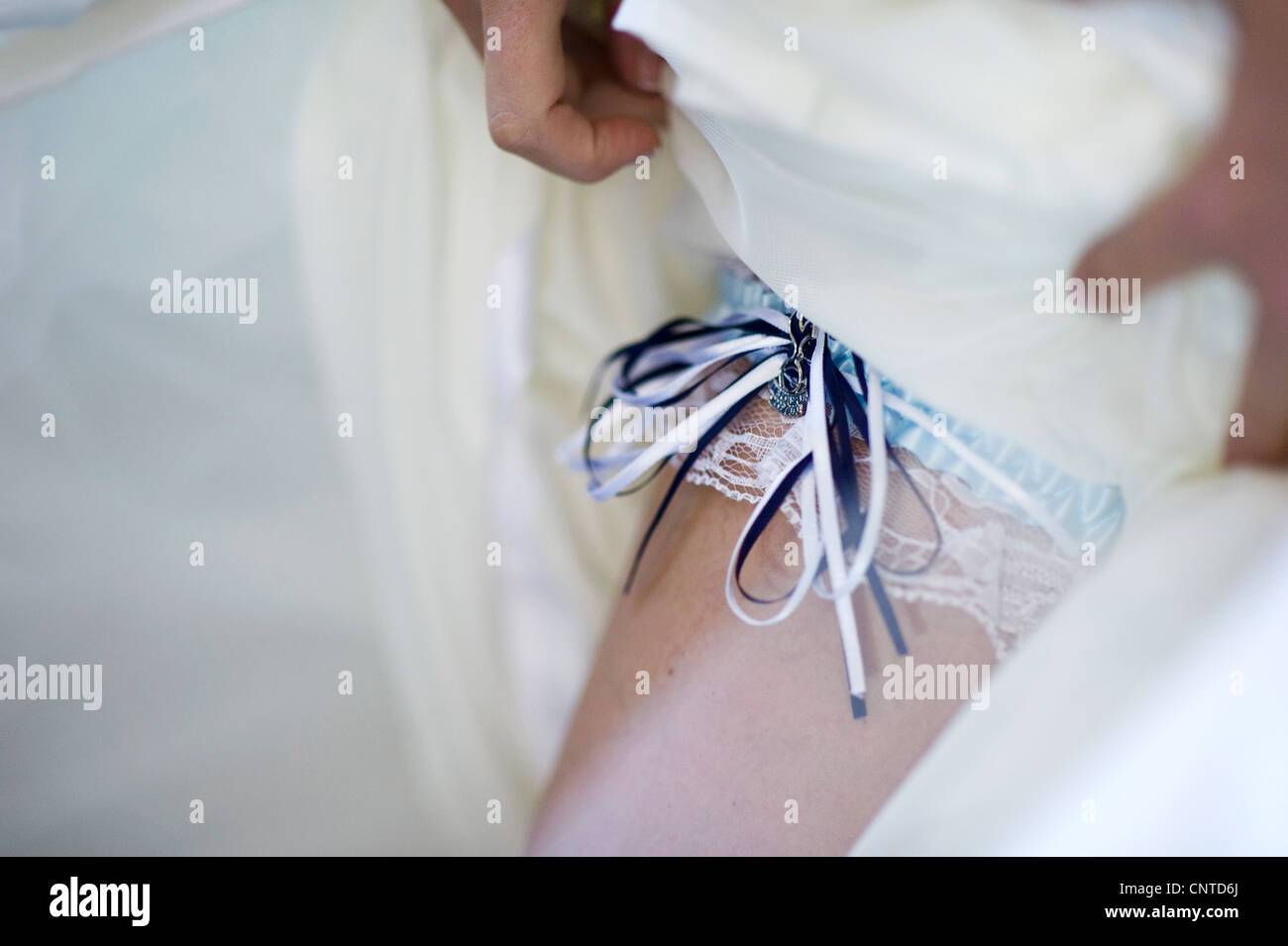 bride wearing traditional wedding garter with blue ribbon and lace