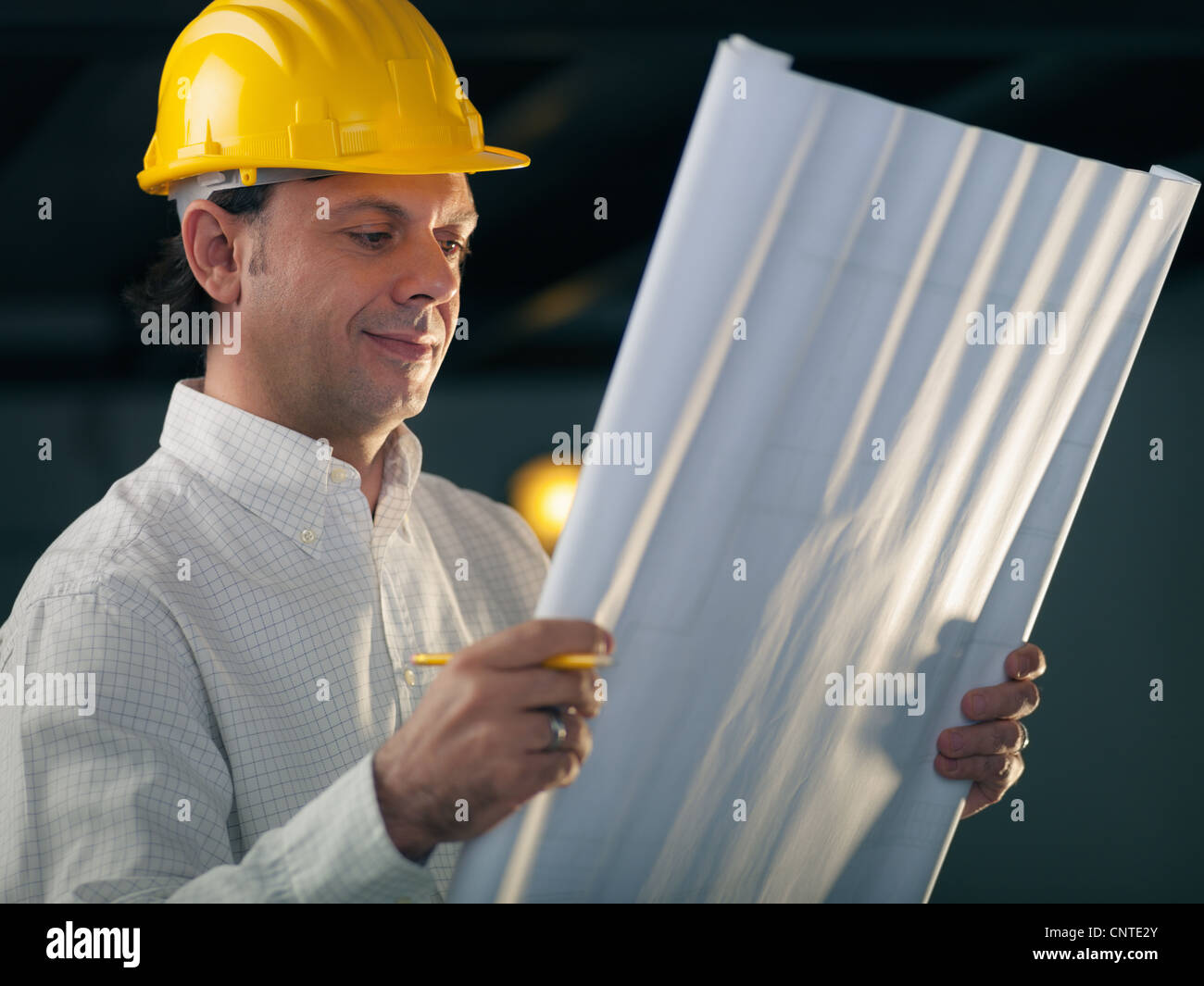 middle aged man working as architect and reading building plan in ...