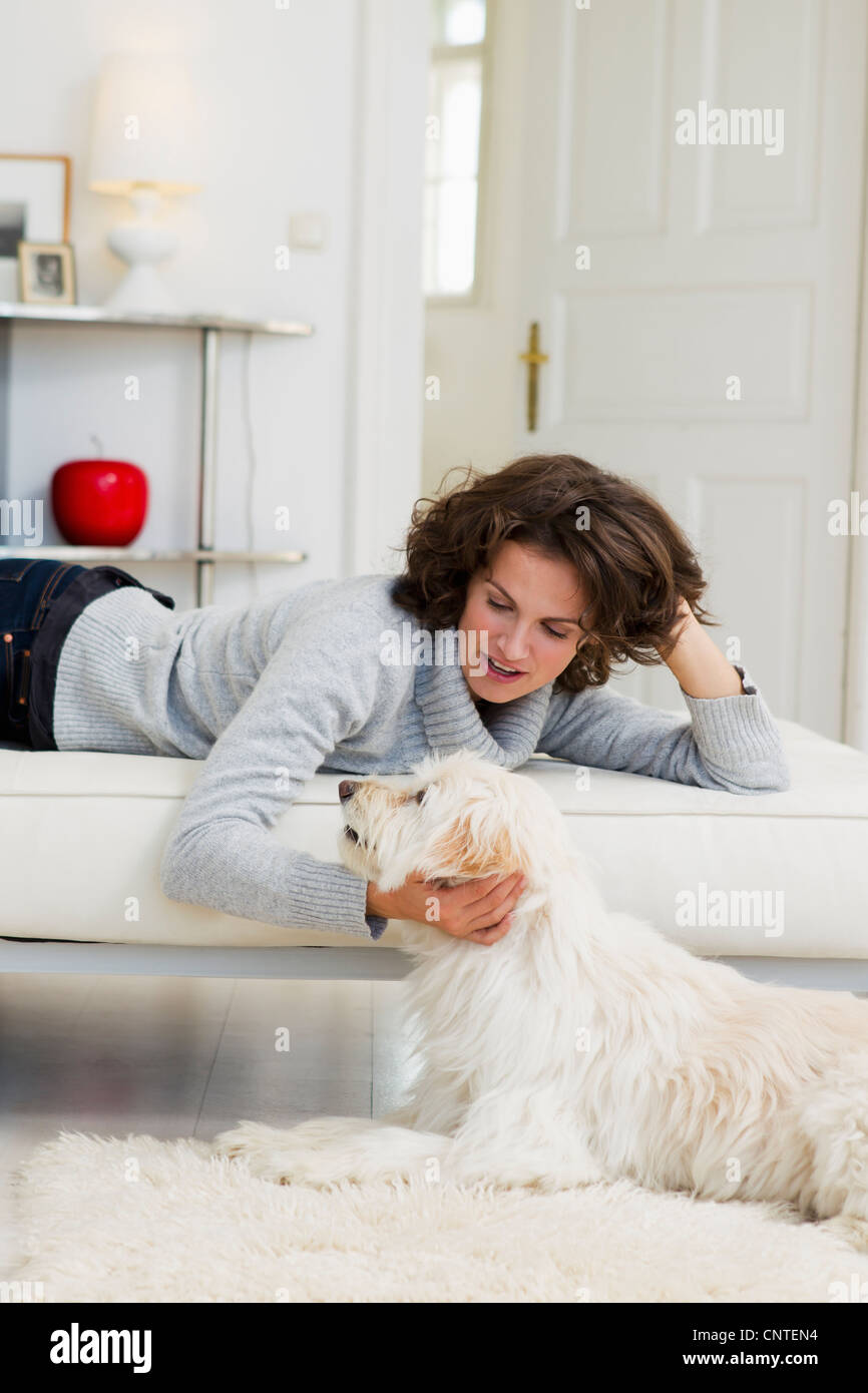 Woman petting dog in living room Stock Photo