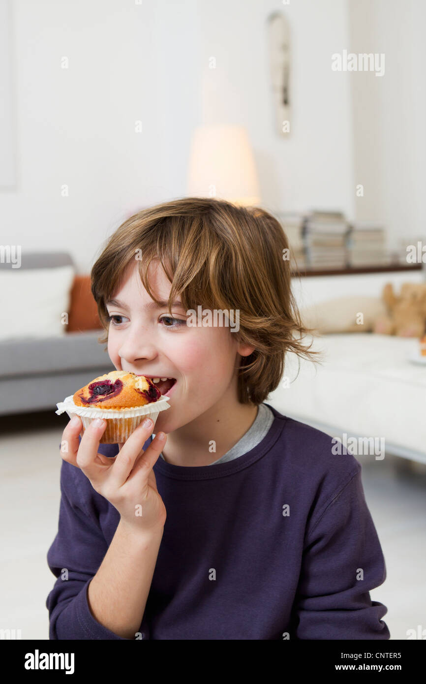 Boy eating muffin in living room Stock Photo Alamy