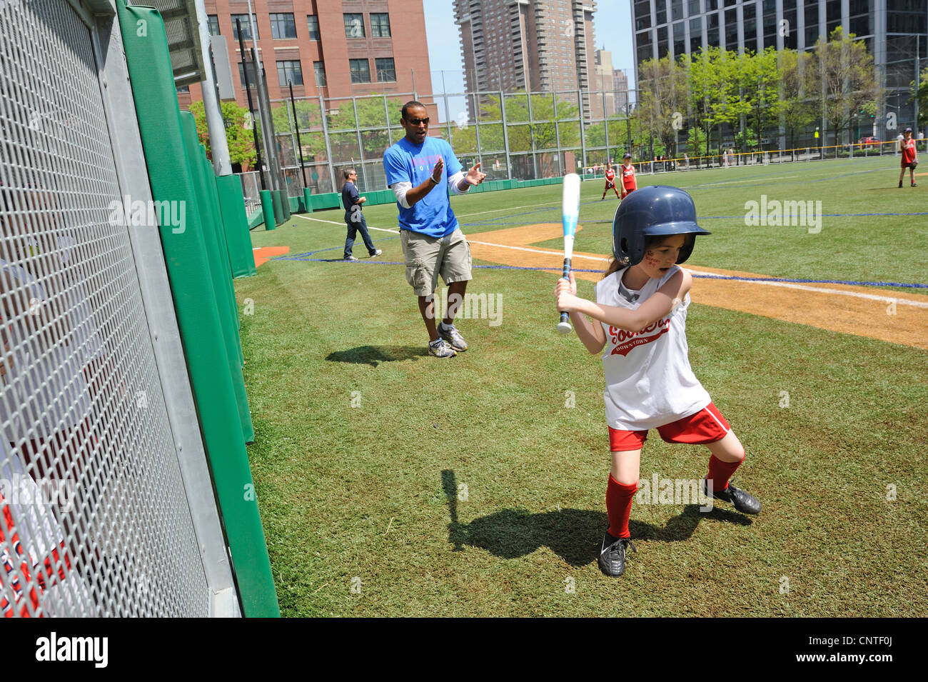A young girl practicing her batting stance during a Little League softball game in Battery Park