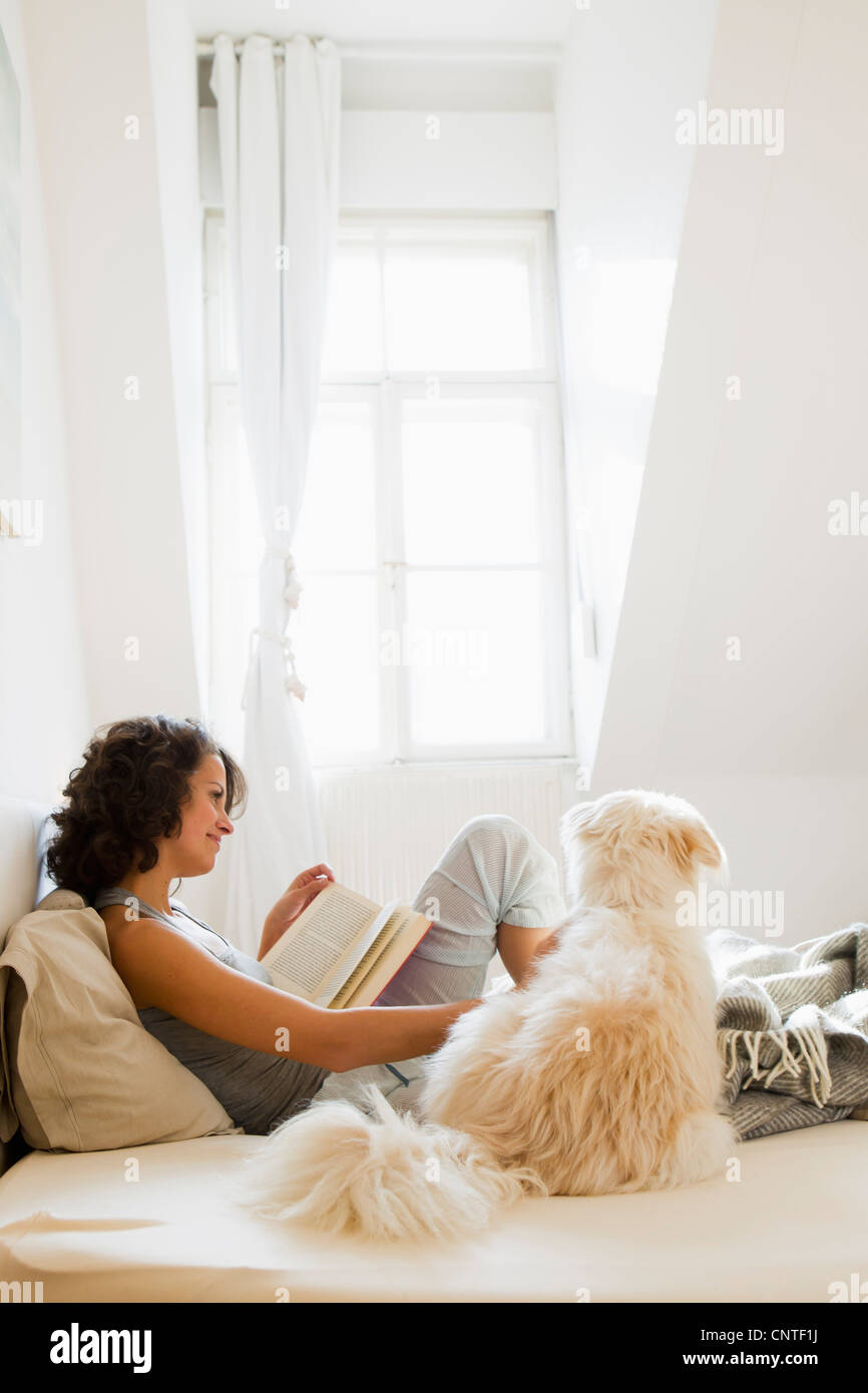 Woman reading in bed with dog Stock Photo