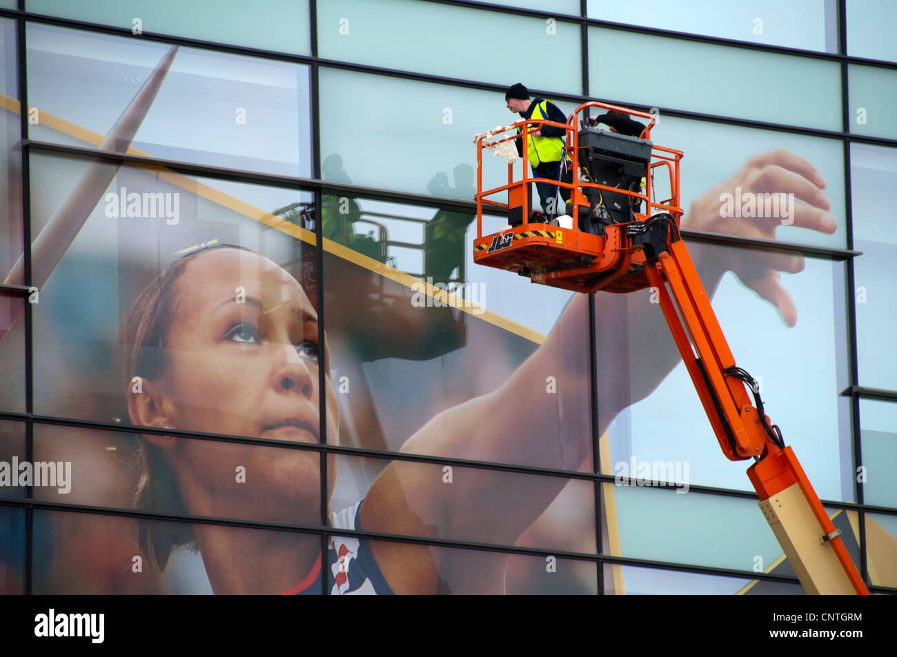 Workers on an access platform installing signs on the BBC's Quay House at MediaCityUK, Salford Quays, Manchester, England, UK Stock Photo