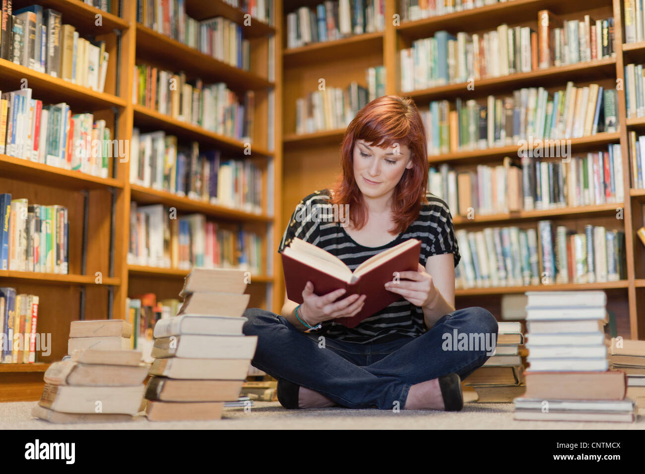 Student in pile of books in library Stock Photo - Alamy