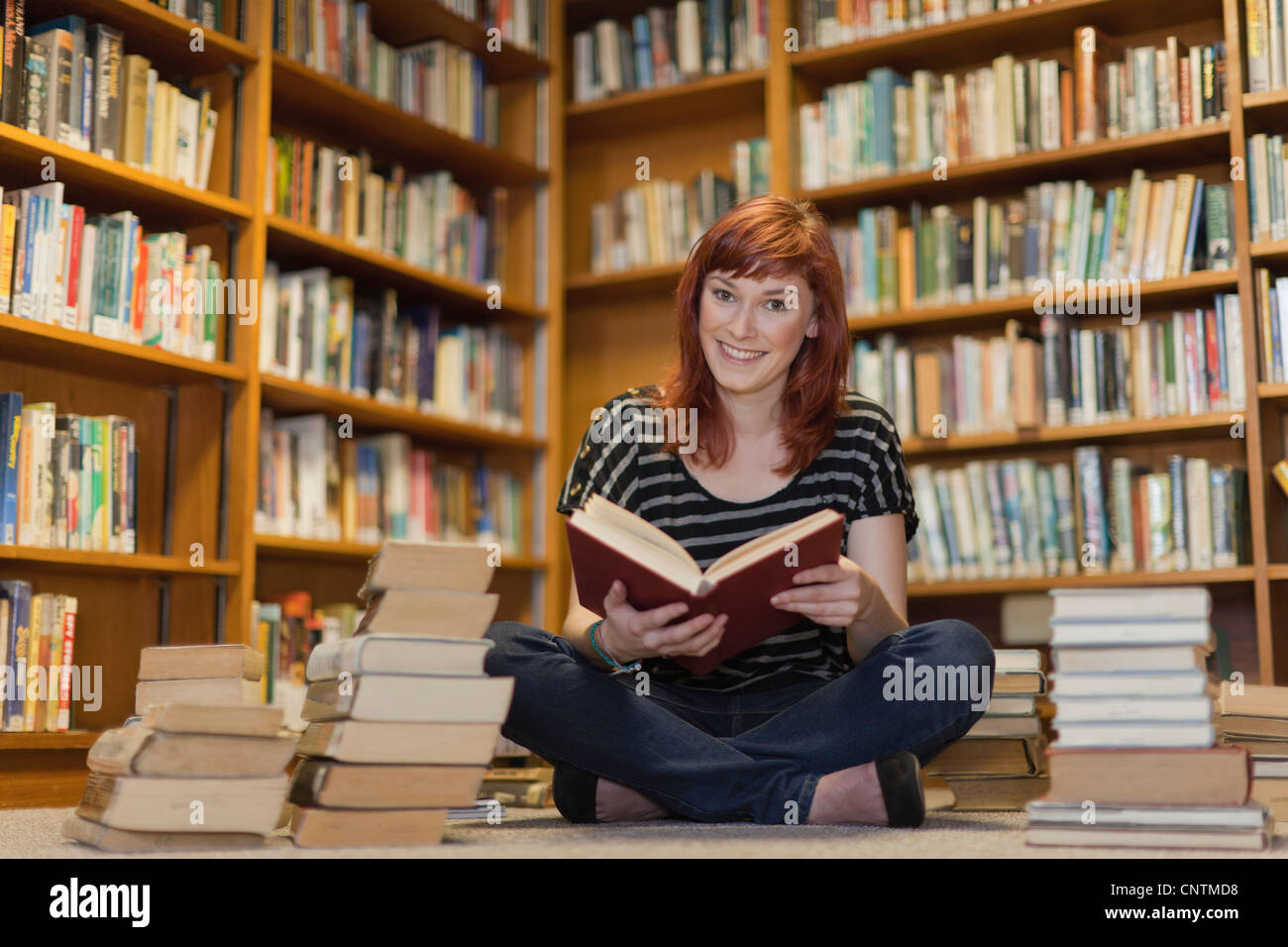 Student in pile of books in library Stock Photo - Alamy