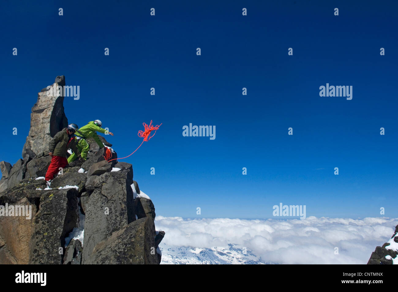two ski alpinists climbing in the mountains, throwing the rope, France, Alps Stock Photo