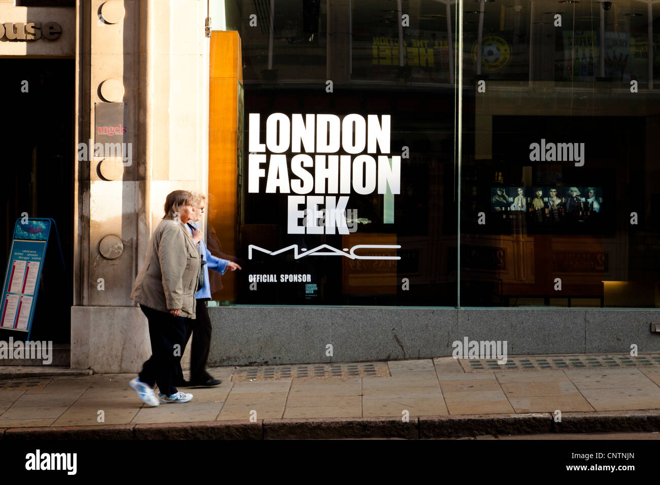 Misspelling due to lost letter. Humorous view of London Fashion Week shop window with two women shoppers and several models on a tv screen, UK Stock Photo