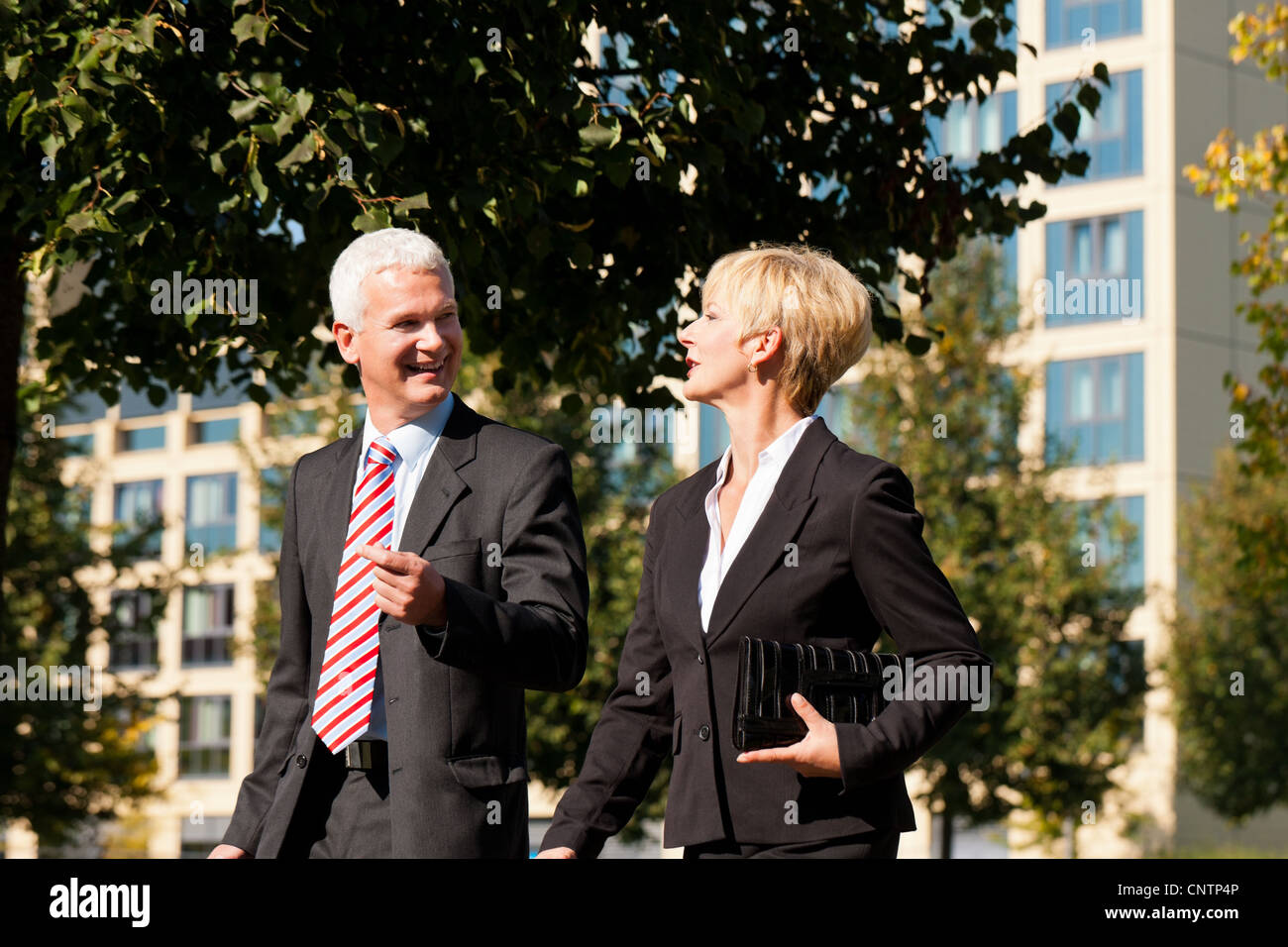 Business people - mature or senior - talking outdoors and walking in a ...