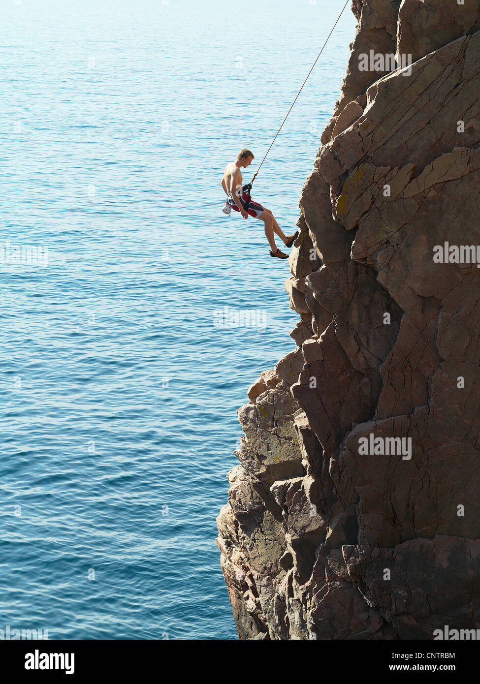 Rock climber rappelling down rock face Stock Photo