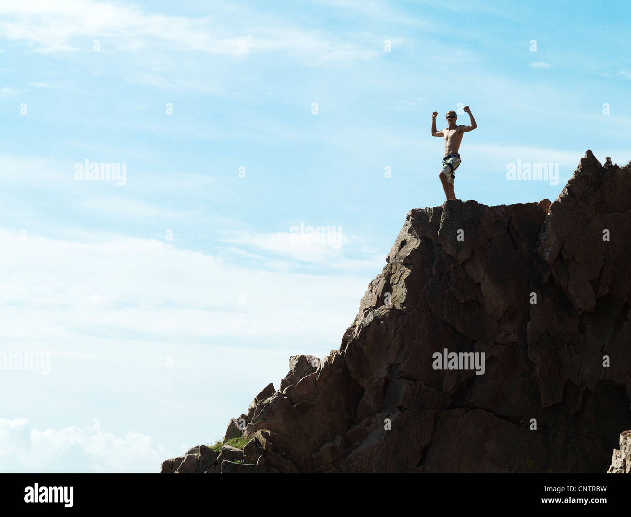 Man cheering on top of rocky hillside Stock Photo