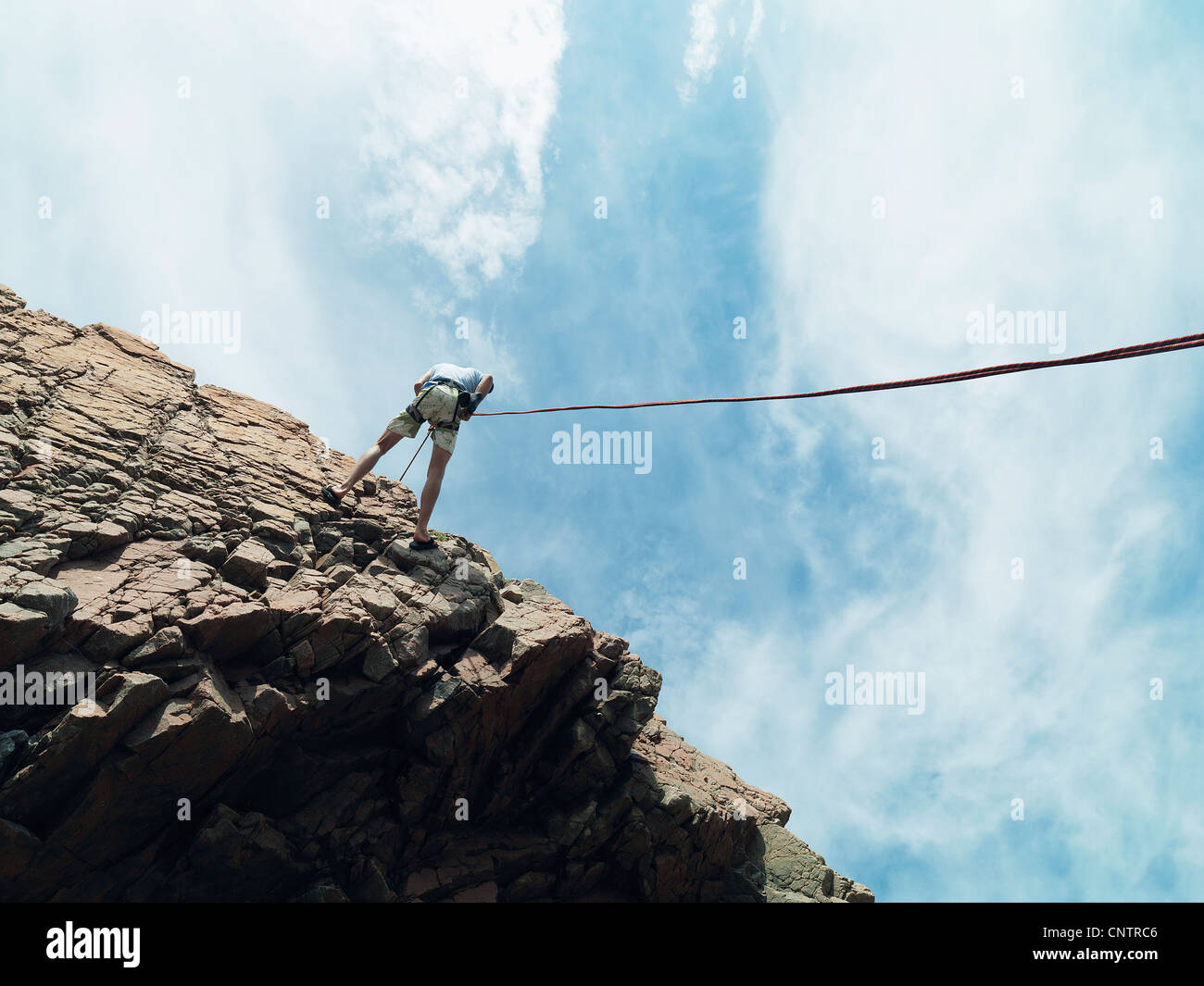 Rock climber rappelling down rock face Stock Photo