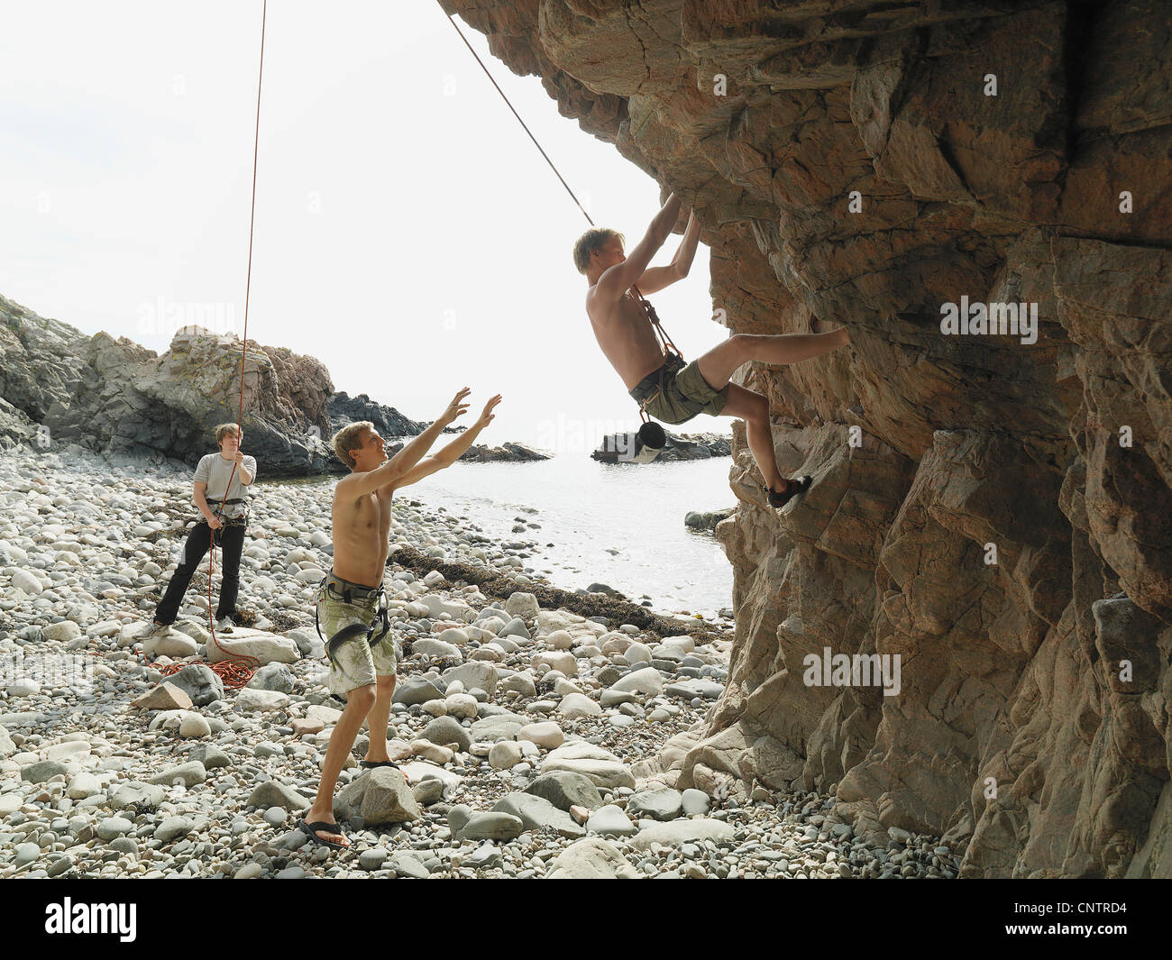 Rock climbers rappelling down rock face Stock Photo