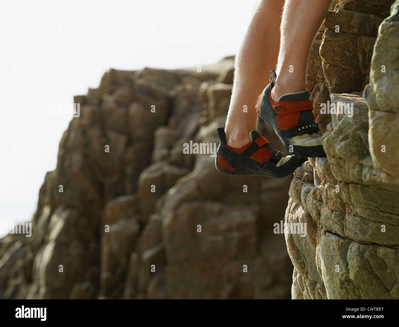 Rock climbers feet on steep rock face Stock Photo