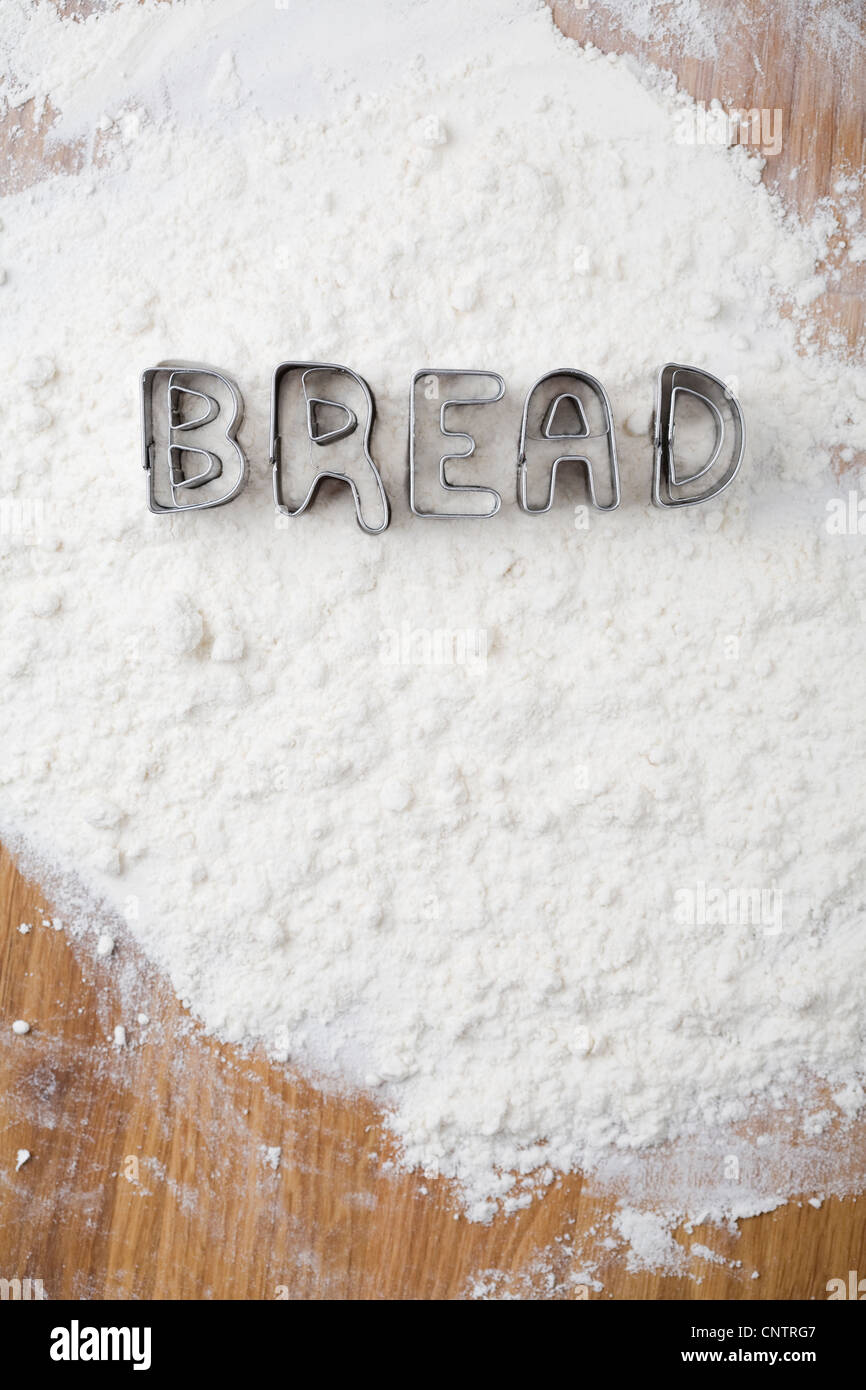 Cookie cutters spelling bread in flour Stock Photo