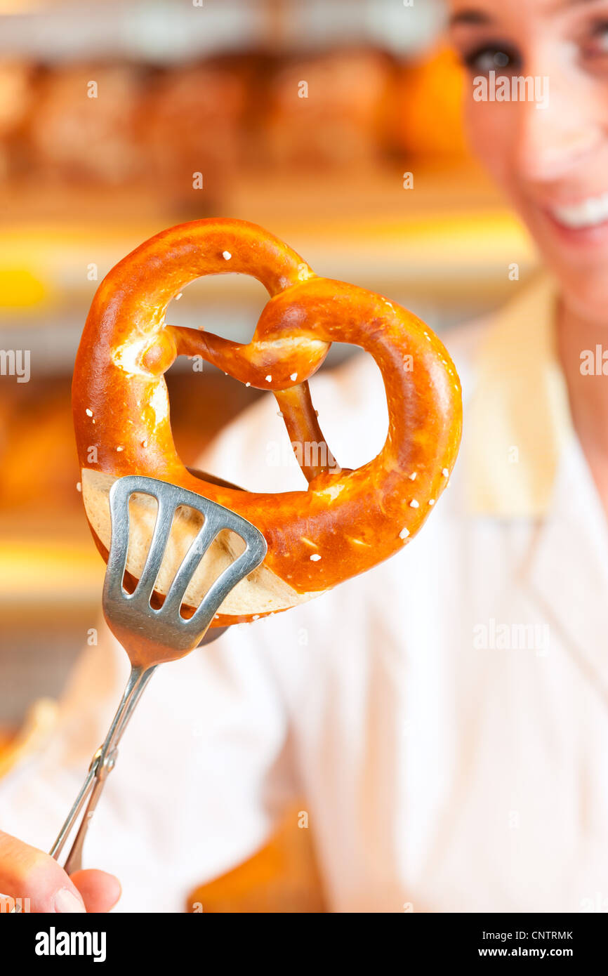 Young salesperson in a bakery is packing bread and pretzels for a