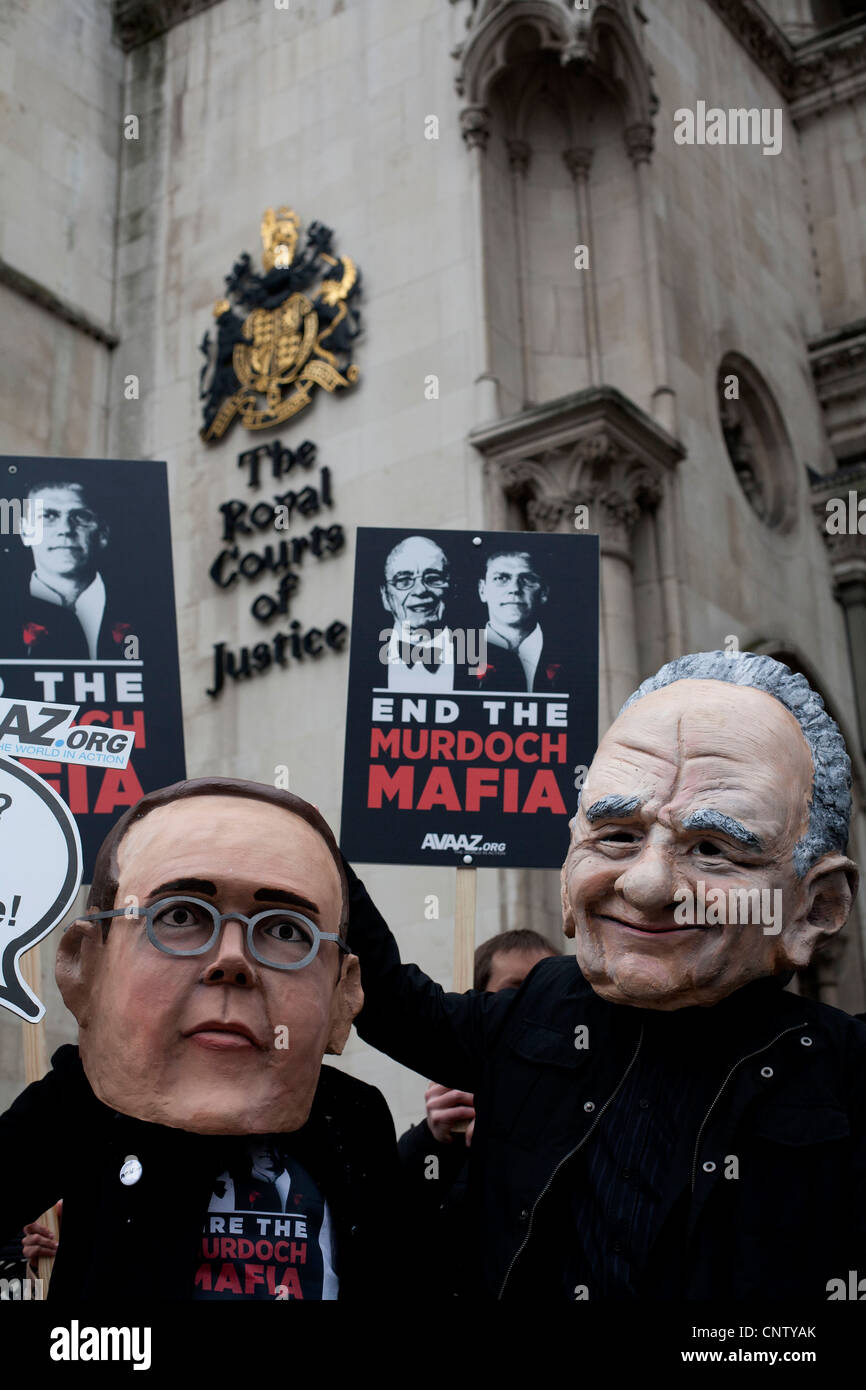 Protesters wearing masks of James Murdoch (L) and his father Rupert (R) demonstrate outside the Leveson Inquiry High Court Stock Photo