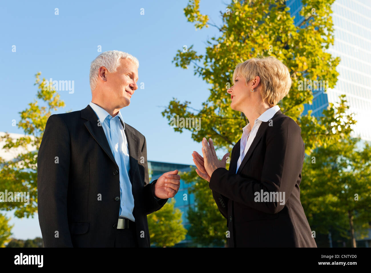 Business people - mature or senior - standing in a park outdoors talking Stock Photo